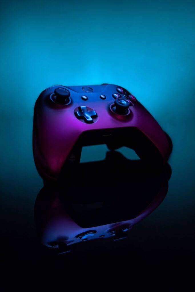 A vibrant gaming controller with a blue and pink reflection on a dark surface, creating a striking visual contrast.